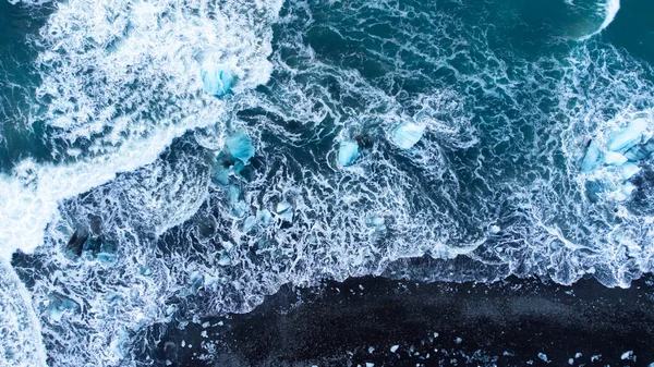 Pure Blue Glacier Ice on Black Sand Beach. Turquoise Sea Water. Diamond Beach in Iceland. High quality photo