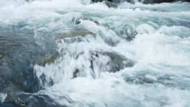 Taş kayaların arasından akan saf su akıntısı. Yaz Günü 'nde Vahşi Dağ Nehri Suyun Sıçrıyor. İzlanda. 8K 'da çekilmiş..