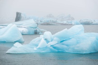 Big pure glacier ice in ocean water. Melting icebergs in foggy weather. Jokulsarlon lagoon in Iceland. Global warming and climate change concept. High quality photo