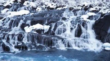 Waterfall in Iceland, Snowy Mountain and Cold River in Winter. Magical Outdoor Winter Time Location, Blue Glacial Water with a Huge Current. Pure Scenic Landscape. Hraunfossar. Shot in 8k Resolution.