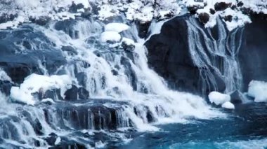 Waterfall in Iceland, Snowy Mountain and Cold River in Winter. Magical Outdoor Winter Time Location, Blue Glacial Water with a Huge Current. Pure Scenic Landscape. Hraunfossar. Shot in 8k Resolution.