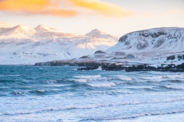 Pure blue ocean water at sunset, Ocean coastline with mountains, Winter landscape with snow, clouds and stormy sea.