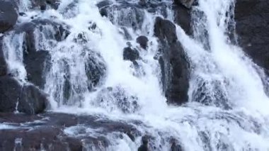 Vahşi dağ nehri taş kayaların arasından akıyor. İzlanda 'nın temiz akıntısı yakın. Ulusal parktaki kayalardan büyük bir şelale. Su arka planı konsepti. 8k çözünürlükte çekiliyor