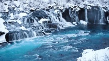 Waterfall in Iceland, Snowy Mountain and Cold River in Winter. Magical Outdoor Winter Time Location, Blue Glacial Water with a Huge Current. Pure Scenic Landscape. Hraunfossar. Shot in 8k Resolution.