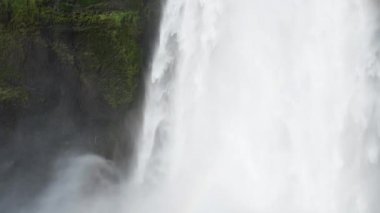 İzlanda 'da Skogafoss şelalesi, uçurumlardan akan su, ünlü cazibe. Kocaman bir dağ nehri. Doğa ilkbahar manzarası. 8K çözünürlükte 4320 peni. Yüksek kalite 4k görüntü