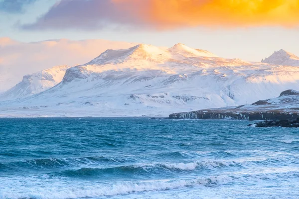 Sunset 'te Atlantik Okyanusu Sahili manzarası. İzlanda 'daki Karlı Dağlar. Fırtınalı Hava Zamanındaki İzlanda fiyortları. Güneşin Ilık Işınları tarafından aydınlatılan bulutlar. Yüksek Kalite Fotoğraf