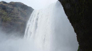 İzlanda 'da Skogafoss şelalesi, uçurumlardan akan su, ünlü cazibe. Kocaman bir dağ nehri. Doğa ilkbahar manzarası. 8K çözünürlükte 4320 peni. Yüksek kalite 4k görüntü