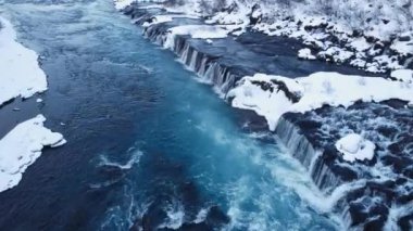 Waterfall in Iceland, Snowy Mountain and Cold River in Winter. Magical Outdoor Winter Time Location, Blue Glacial Water with a Huge Current. Pure Scenic Landscape. Hraunfossar. 