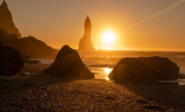 Black Sand Beach In Iceland. Sunset over Volcanic Cliffside. Stunning Ocean Coast. Unusual Pure Nature. Famous Tourist Location near Vik. Traveling in Iceland. Shot in High Resolution.