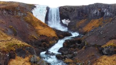 İzlanda 'da büyük manzaralı bir şelale. Dağlardaki saf buzul nehri. Sonbahar renkleri hava görüntüsü 4K. Yüksek kalite 4k görüntü