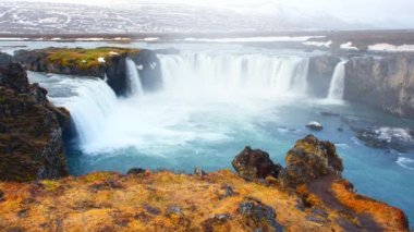 İzlanda 'da şelale. Saf buzul suyu yüksek kayalıklardan akıyor. Kocaman bir su akıntısı. Godafoss ünlü seyahat yeri. İlham, bahar doğası 4k, 8k çözünürlükte çekim. Yüksek kalite 4k