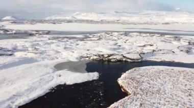 Kış mevsiminde İzlanda dağları. Donmuş nehirler ve karla kaplı dağlar. Hava uçuş görüntüleri. Destansı doğa manzarası. Yüksek kalite 4k görüntü