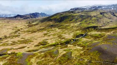 Nehirli alışılmadık volkanik manzara, ilkbaharın başlarında yeşil yosunlarla kaplı volkanik dağ arazisi, İzlanda 'da el değmemiş saf doğa, destansı hava manzarası.