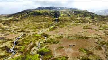 Nehirli alışılmadık volkanik manzara, ilkbaharın başlarında yeşil yosunlarla kaplı volkanik dağ arazisi, İzlanda 'da el değmemiş saf doğa, destansı hava manzarası.