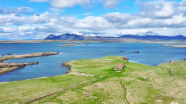 Okyanus kıyısındaki çiftlik evi. İzlanda kırsalının manzarası. İzlanda 'daki klasik çiftlik. Yazın İzlanda fiyortları. Turkuaz su ve yeşil çimen. Hava görüntüsü 4k.