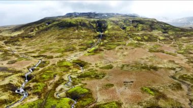 Nehirli alışılmadık volkanik manzara, ilkbaharın başlarında yeşil yosunlarla kaplı volkanik dağ arazisi, İzlanda 'da el değmemiş saf doğa, destansı hava manzarası.
