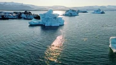 İzlanda Turkuaz Buzul Gölü 'nde Büyük Buz Parçaları Gün Batımında eriyen bir buzuldan oluşan açık mavi buzdağları Şafakta Arktik Manzarası Epic Aerial View. Yüksek kalite 4k görüntü