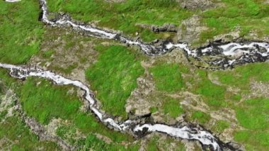 İzlanda 'nın yaz aylarındaki dağlarının yamaçlarından akan dağ nehri devasa volkanik tepeler ve birçok şelale saf buzul suyu destansı hava manzarası 4k. Yüksek kalite 4k görüntü