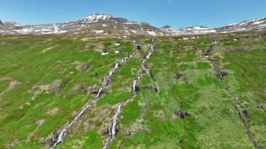 İzlanda 'nın yaz aylarındaki dağlarının yamaçlarından akan dağ nehri devasa volkanik tepeler ve birçok şelale saf buzul suyu destansı hava manzarası 4k. Yüksek kalite 4k görüntü