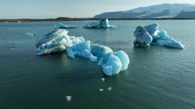 İzlanda Turkuaz Buzul Gölü 'nde Büyük Buz Parçaları Gün Batımında eriyen bir buzuldan oluşan açık mavi buzdağları Şafakta Arktik Manzarası Epic Aerial View. Yüksek kalite 4k görüntü