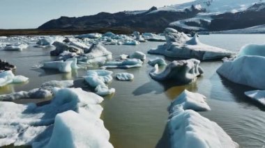 Buzul gölünde büyük buz kütleleri yüzer. İzlanda 'da manzara. Berrak mavi buzdağları. Epic Aerial View Şafak 4 'te..