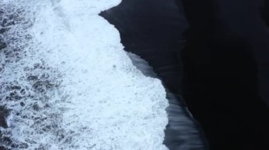 Reynisfjara Vik 'te büyük dalgaları olan İzlanda siyah kumsalı. Hava sineması 4K videosu. Güzel İzlanda doğa kıyısı yukarıdan. Yüksek kalite 4k görüntü