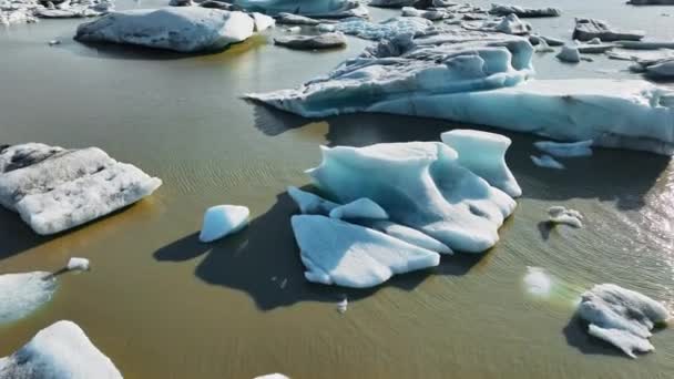 アイスランドのブラウン氷河ラグーンに浮かぶ氷の塊地球温暖化と気候変動氷塊が氷解する氷河から形成される青い氷河北極の風景壮大な空中ビュー夜明け4K — ストック動画