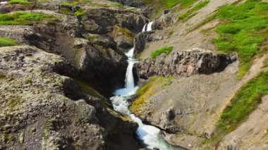 Dağlık bölgelerde şelale, kanyonun içindeki dağ nehri, destansı hava aracı görüntüsü. Yaz mevsiminde İzlanda. Yüksek kalite 4k görüntü