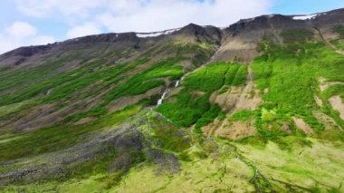 Yeşil çalılar ve yosunlarla çevrili birçok şelale var. Dağ nehri tepeden aşağı akar. Dağlardaki nehir. İzlanda 'nın renkli doğası. Epic Aerial Landscape 4k.