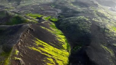 İzlanda 'daki dağlık arazi, güzel volkanik dağ, alışılmadık doğa manzarası. Yeşil yosunlu siyah tepeler. 4k
