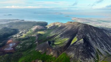 İzlanda 'daki dağlık arazi, güzel volkanik dağ, alışılmadık doğa manzarası. Yeşil yosunlu siyah tepeler. 4k
