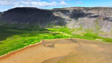İzlanda 'da okyanusta altın kumu ve yeşil otları olan bir sahil. Kuzey cennetinin alışılmadık ve büyüleyici bir manzarası, sarı kum ve turkuaz su. Doğa hava görüntüsü.
