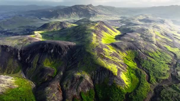 在落日的光芒中覆盖着绿色苔藓的山脉 巨大的黑色火山山 不同寻常的自然景观 冰岛高地的自然景色4K — 图库视频影像