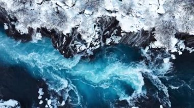 İzlanda 'da şelale, kışın soğuk nehri olan karlı dağ, kar ve buzun büyülü yeri, büyük akıntılı mavi buzul suyu. Saf Manzara Manzarası. Hraunfossar. 4k görüntü