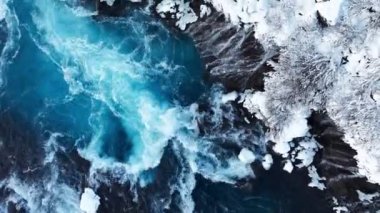 İzlanda 'da şelale, kışın soğuk nehri olan karlı dağ, kar ve buzun büyülü yeri, büyük akıntılı mavi buzul suyu. Saf Manzara Manzarası. Hraunfossar. 4k görüntü