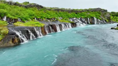 Birçok küçük şelalesi olan mavi buzul nehri, çarpıcı kuş bakışı manzaralı soğuk turkuaz buzul nehri yaz mevsiminde birçok deresi olan İzlanda, Hraunfossar ve Barnafoss. 4k 