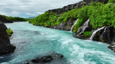 Birçok küçük şelalesi olan mavi buzul nehri, çarpıcı kuş bakışı manzaralı soğuk turkuaz buzul nehri yaz mevsiminde birçok deresi olan İzlanda, Hraunfossar ve Barnafoss. 4k 