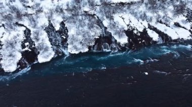 İzlanda 'da şelale, kışın soğuk nehri olan karlı dağ, kar ve buzun büyülü yeri, büyük akıntılı mavi buzul suyu. Saf Manzara Manzarası. Hraunfossar. 4k görüntü
