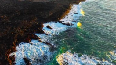 Atlantik Okyanusu kıyıları rüzgarlı havada, büyük dalgalar keskin siyah bazalt kayalara vuruyor, gün batımında İzlanda kıyıları, açık denizlerde fırtına. Yüksek kalite 4k görüntü