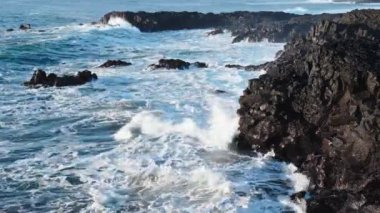 Kıyıya devasa dalgalar çarpar İzlanda 'da Rocky Okyanusu kıyıları, Basalt kayaları tehlikeli kayaların üzerinde dalgaların müthiş gücü. Yüksek kalite 4k görüntü