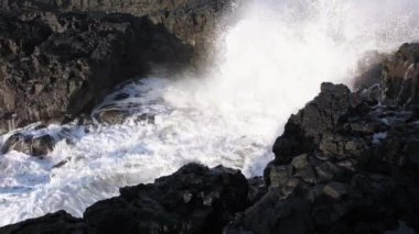 Kıyıya devasa dalgalar çarpar İzlanda 'da Rocky Okyanusu kıyıları, Basalt kayaları tehlikeli kayaların üzerinde dalgaların müthiş gücü. Yüksek kalite 4k görüntü