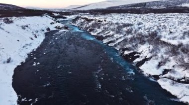 Saf turkuaz su, dev bir akıntısı olan buzul nehri İzlanda 'da şelale, kışın donmuş şelale, kar ve buzun büyülü kış mekanı, popüler turizm merkezi.