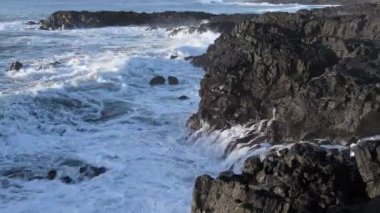 Kıyıya devasa dalgalar çarpar İzlanda 'da Rocky Okyanusu kıyıları, Basalt kayaları tehlikeli kayaların üzerinde dalgaların müthiş gücü. Yüksek kalite 4k görüntü