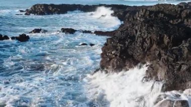 Kıyıya devasa dalgalar çarpar İzlanda 'da Rocky Okyanusu kıyıları, Basalt kayaları tehlikeli kayaların üzerinde dalgaların müthiş gücü. Yüksek kalite 4k görüntü