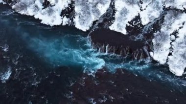 İzlanda 'da şelale, kışın soğuk nehri olan karlı dağ, kar ve buzun büyülü yeri, büyük akıntılı mavi buzul suyu. Saf Manzara Manzarası. Hraunfossar. 4k görüntü