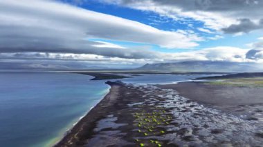 İzlanda 'da benzersiz siyah kumlu sahil. Yeşil küçük tepeleri olan eşsiz kıyı şeridi. 4k' lik olağanüstü soyut manzarası var.