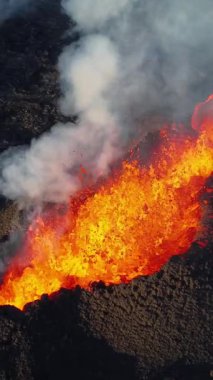 Dikey Ekran: 2023 'te volkan patlaması, İzlanda' da yerden kırmızı lav püskürmesi. Yeni aktif bir volkan oluşumu. Hava görüntüleri. Sosyal medya için çekim.