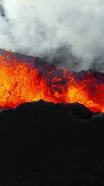 Dikey Ekran: 2023 'te volkan patlaması, İzlanda' da yerden kırmızı lav püskürmesi. Yeni aktif bir volkan oluşumu. Hava görüntüleri. Sosyal medya için çekim.