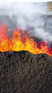 Dikey Ekran: 2023 'te volkan patlaması, İzlanda' da yerden kırmızı lav püskürmesi. Yeni aktif bir volkan oluşumu. Hava görüntüleri. Sosyal medya için çekim.