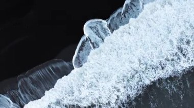 Doğadaki soyut şablon, çarpışan dalgalarla siyah kum volkanik plajının havadan görünüşü, gerçeküstü doğa çizimi, sakin ve sakin manzara, İzlanda 'nın ünlü simgesi. Yüksek kalite 4k görüntü